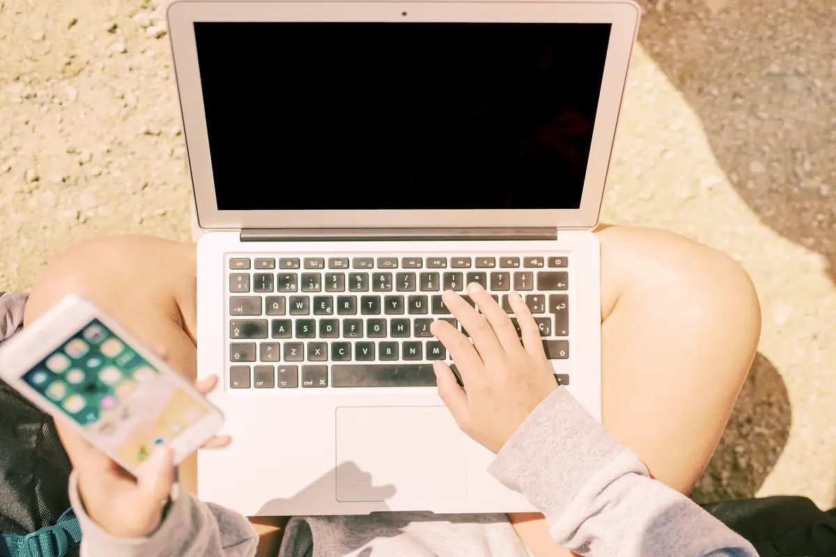 hands of freelancer typing on laptop while using smartphone 