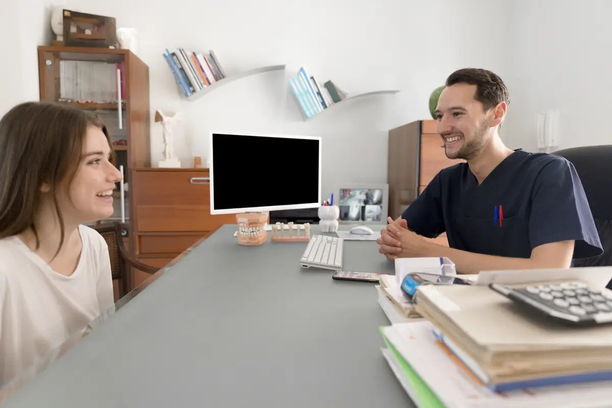 Happy patient consulting to male dentist at dental clinic