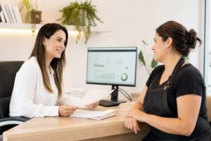 Contadora especializada conversando com dona de salão de beleza sobre a troca de contabilidade em escritório claro e moderno
